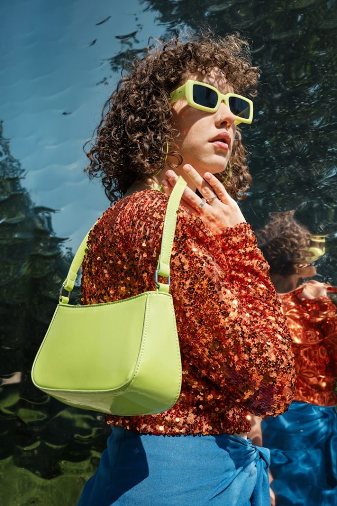 Lifestyle-Shop Frau mit lockigem Haar trägt eine helle Handtasche.
