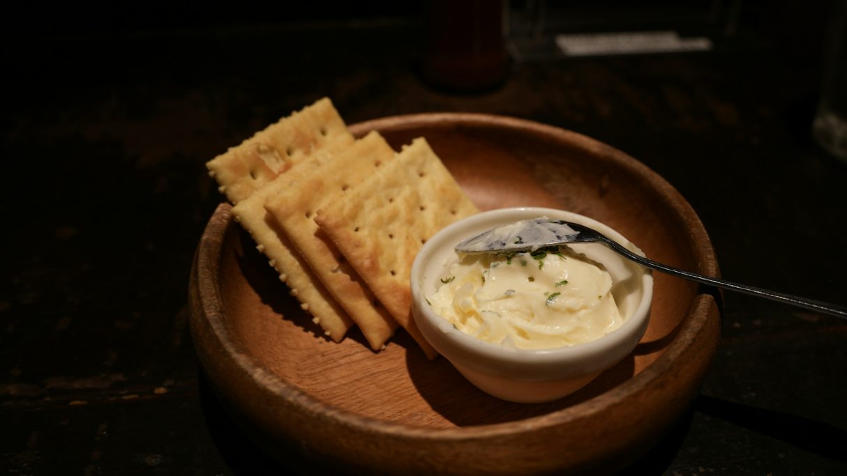 Gourmet-Shop Ein Holzschälchen mit Cracker und einem Dip